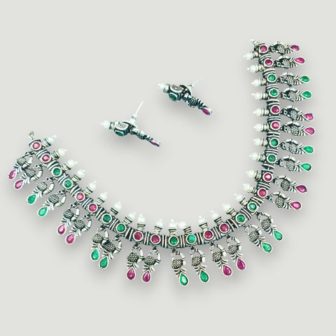 Silver necklace with green and pink stones on a light gray background