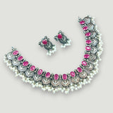 Necklace and earrings set with pink stones on a light gray background