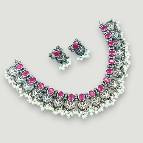 Necklace and earrings set with pink stones on a light gray background