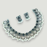 Necklace and earrings set with black stones and white beads on a light gray background