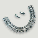 Silver necklace and earrings set on a light gray background