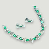 Jewelry set with emerald green stones on a light gray background