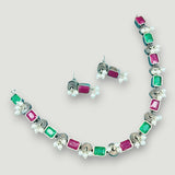 Jewelry set with necklace and earrings featuring green and pink gemstones on a light gray background