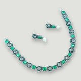Necklace and earrings set with green gemstones on a light gray background