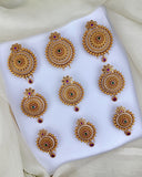 Set of gold earrings with red gemstones on a white fabric background