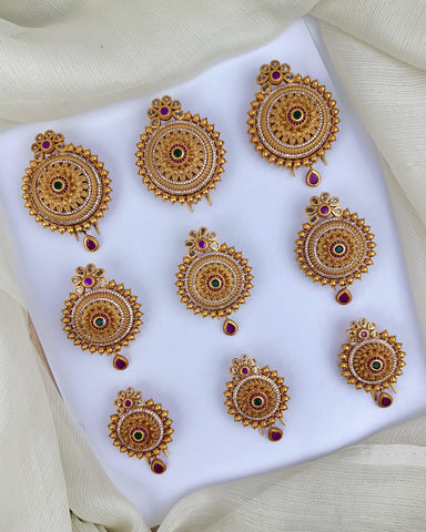 Set of gold earrings with red gemstones on a white fabric background