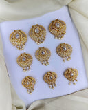 Set of gold earrings with intricate designs on a white platform.