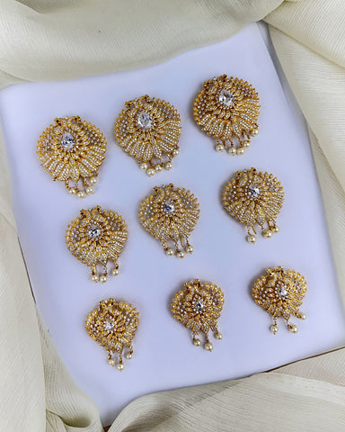 Set of gold earrings with intricate designs on a white platform.
