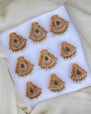 Set of gold and green gemstone earrings on a white fabric background