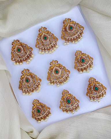 Set of gold and green gemstone earrings on a white fabric background