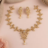 Gold-toned bridal jewelry set featuring a necklace, matching earrings, and a bracelet, all decorated with clear rhinestones and white faux pearls, arranged on a soft pink background with neutral fabric props.