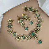 Ornate necklace with green gemstones and gold accents on a plain background