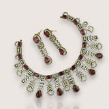 Necklace and earrings set with red gemstones on a light background