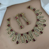Ornate jewelry set with red gemstones on a neutral background