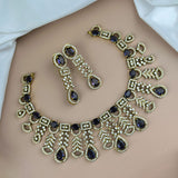 Ornate necklace and earrings with dark gemstones on a plain background