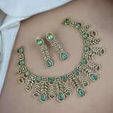 Jewelry set with necklace and earrings featuring green gemstones and gold accents on a neutral background.