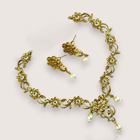 Gold necklace and earrings set on a light pink background