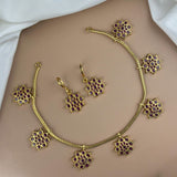 Gold jewelry set with floral designs and red stones on a white background