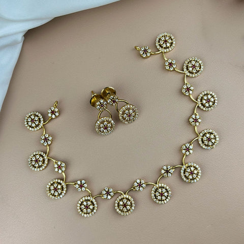 Gold necklace and earrings on a neutral background