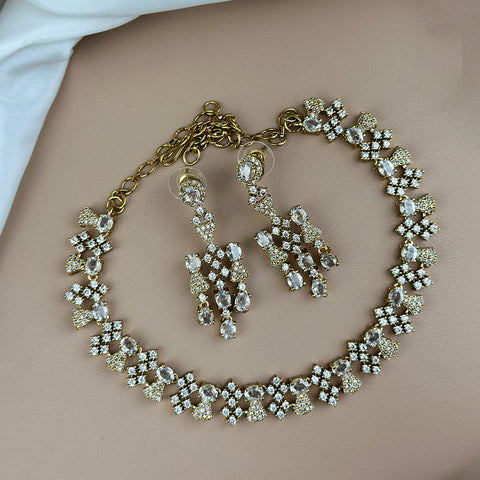 Gold jewelry set with necklace and earrings on a neutral background