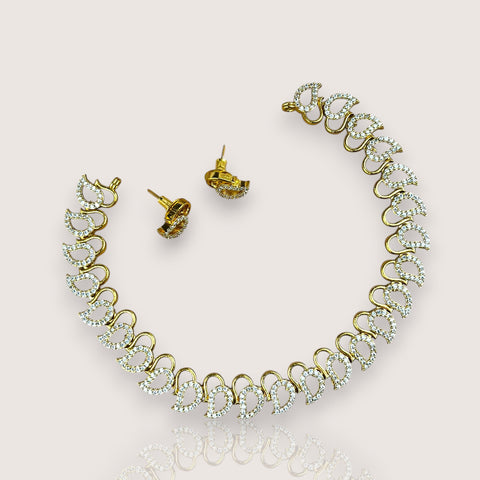 Gold necklace and earrings set on a light pink background