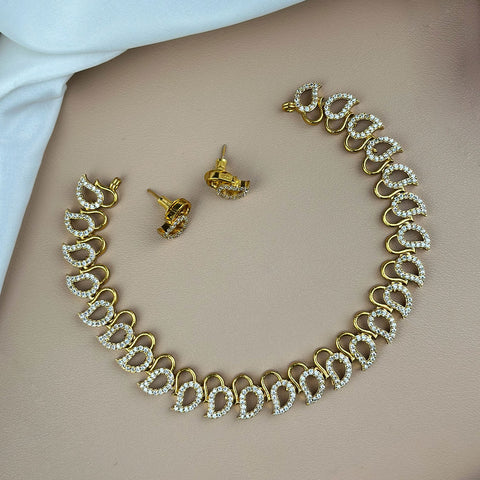 Gold necklace and earrings on a beige surface
