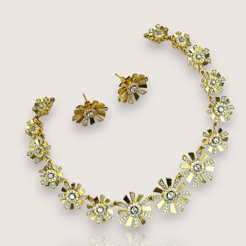 Gold necklace and earrings with floral designs on a light gray background