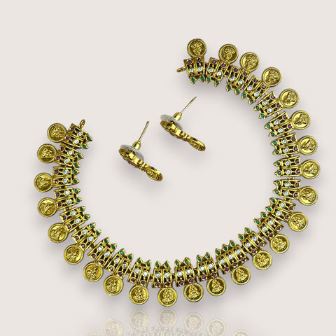 Gold earrings with coin and gemstone design on a light beige background