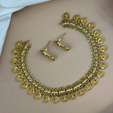 Gold necklace and earrings on a plain background