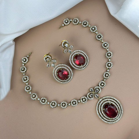 Jewelry set with necklace and earrings featuring red gemstones on a plain background