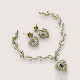 Gold necklace and earrings with gemstones on a light background