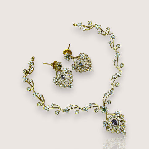 Gold necklace and earrings with gemstones on a light background