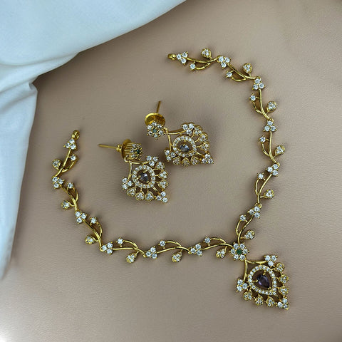Gold necklace and earrings set on a neutral background