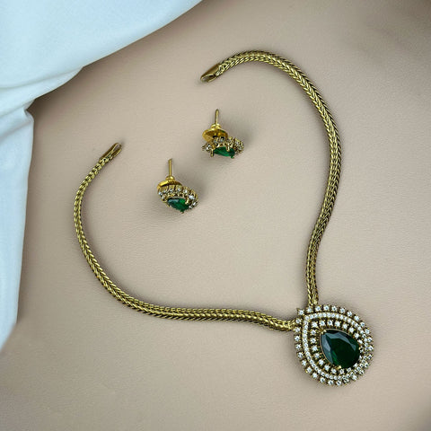 Gold necklace with green gemstones on a plain background
