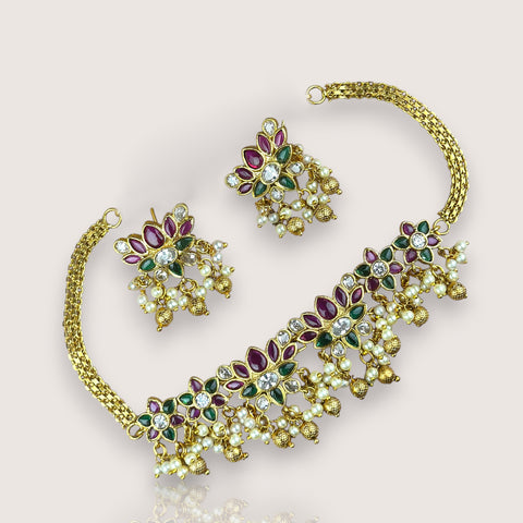 Gold jewelry set with pearls and gemstones on a light background