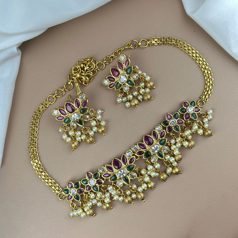 Gold necklace and earrings set on a plain background
