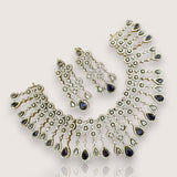 Ornate necklace and earrings with blue gemstones on a light gray background