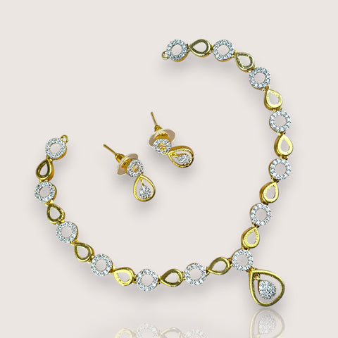 Gold necklace and earrings set on a light gray background