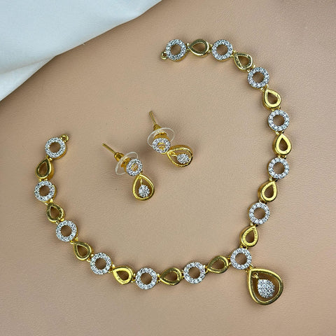 Gold necklace and earrings set on a beige surface