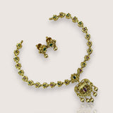 Gold necklace with floral design and embedded gemstones on a light background