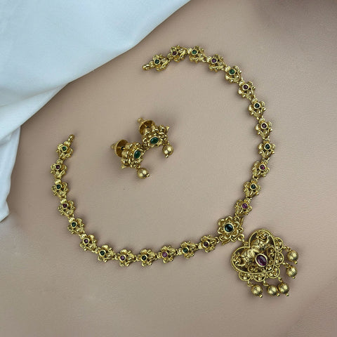 Gold necklace and earrings on a plain background