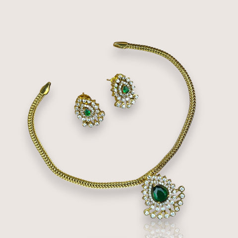 Gold necklace with green gemstones on a light beige background