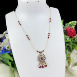 Necklace with red beads and a decorative pendant on a mannequin bust with flowers in the background
