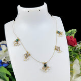 Delicate necklace with green and gold accents on a white mannequin bust with flowers in the background