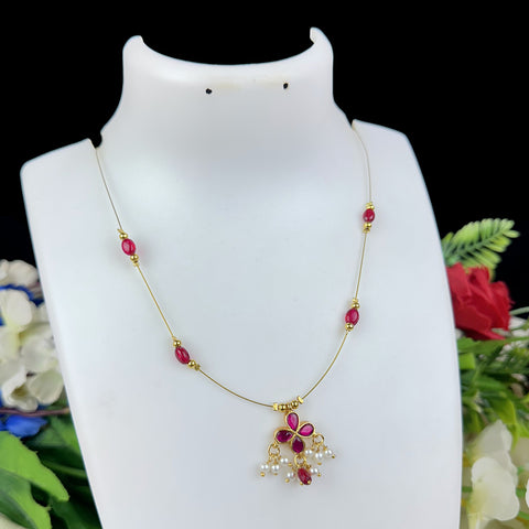 Necklace with red and gold beads on a white mannequin bust with flowers in the background