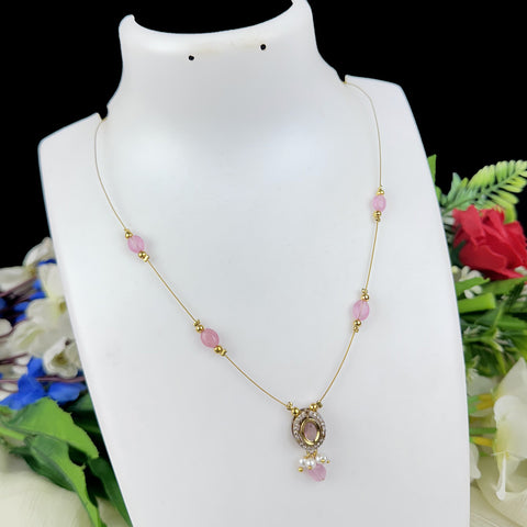 Necklace with pink beads and a pendant on a mannequin bust with flowers in the background