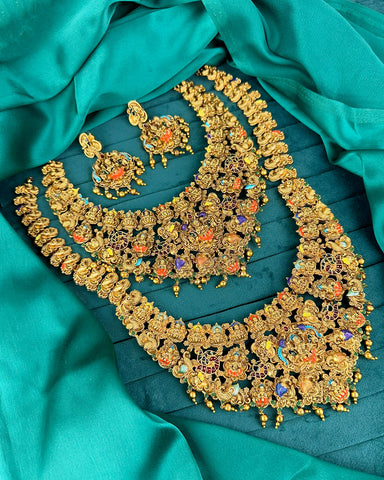 Gold jewelry set with colorful stones on a teal fabric background