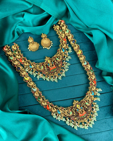 Ornate gold necklace with colorful stones on a teal fabric background