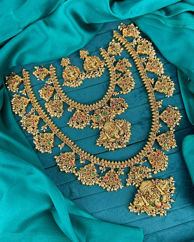 Gold jewelry set with necklaces and earrings on a teal fabric background