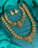 Ornate gold necklace and earrings on a teal fabric background